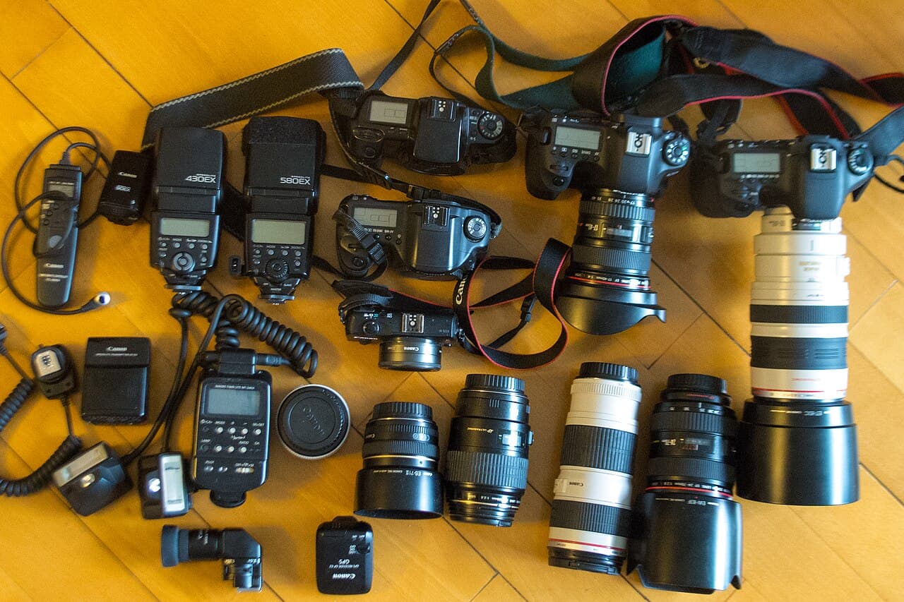 A collection of Canon EOS camera bodies, lenses, and flash units laid out together