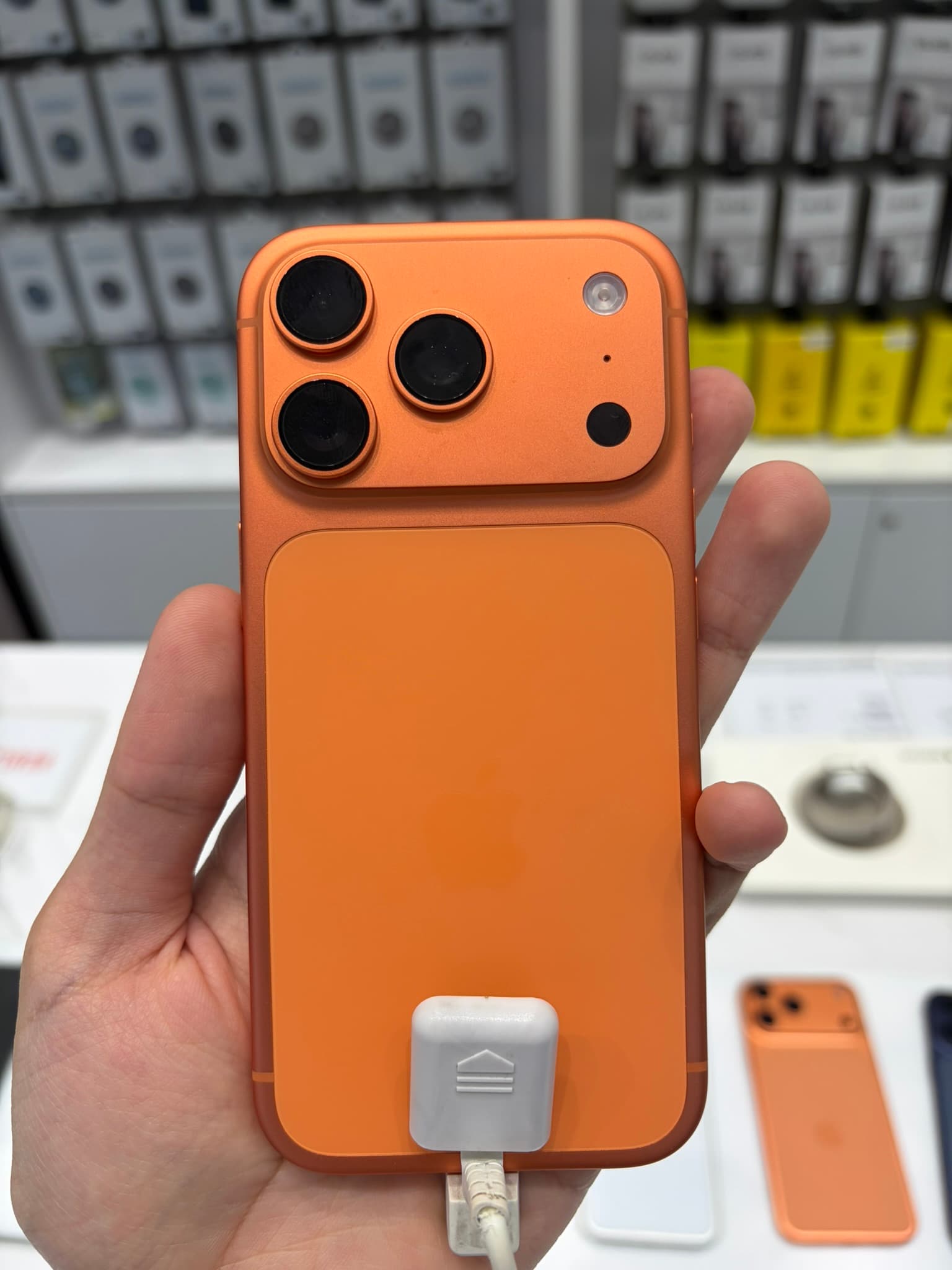 Rear of an Apple iPhone 17 Pro in Cosmic Orange, showing the full-width raised camera plateau with three lenses