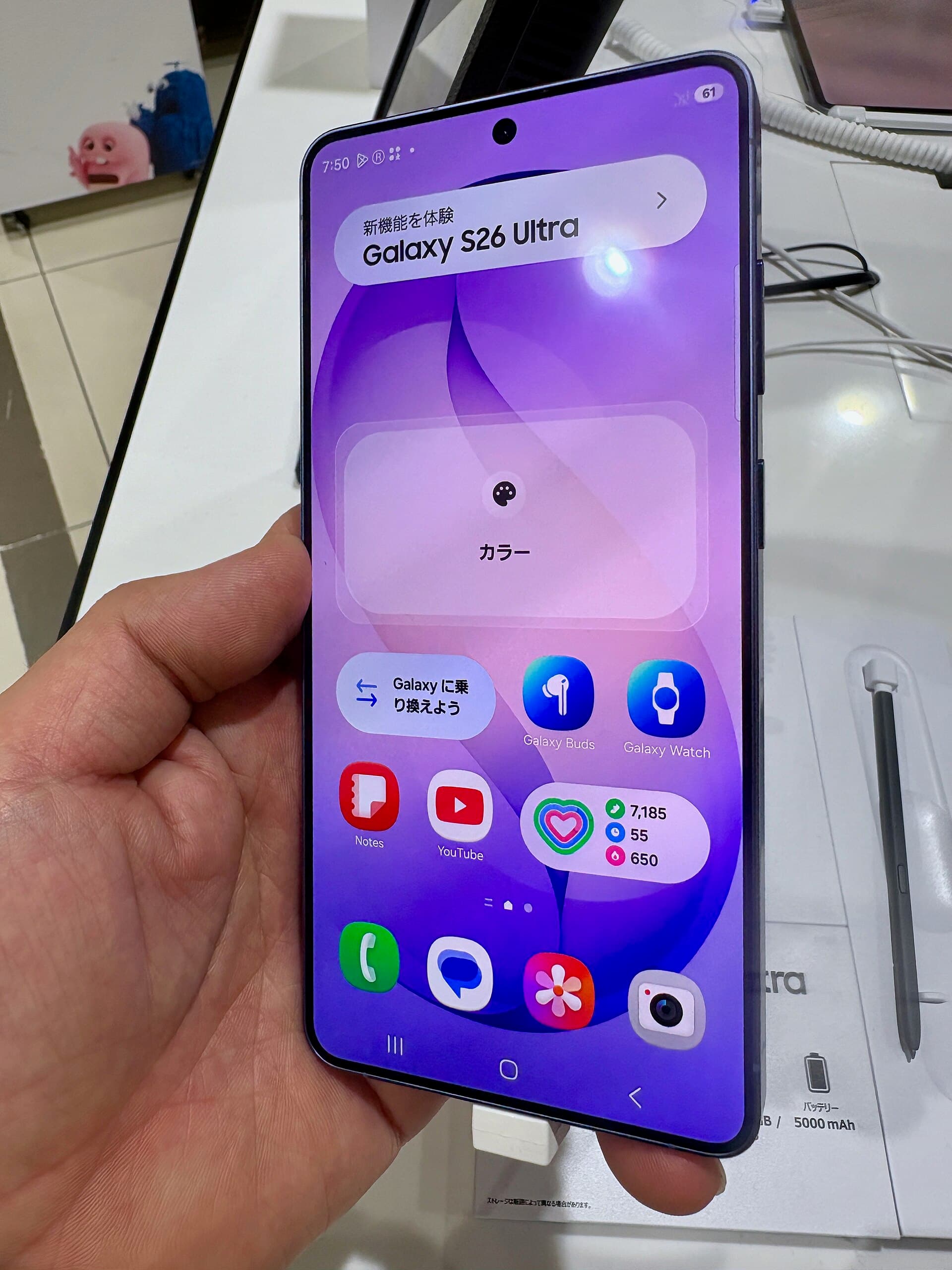 Samsung Galaxy S26 Ultra held in one hand, screen on, at an electronics retail store